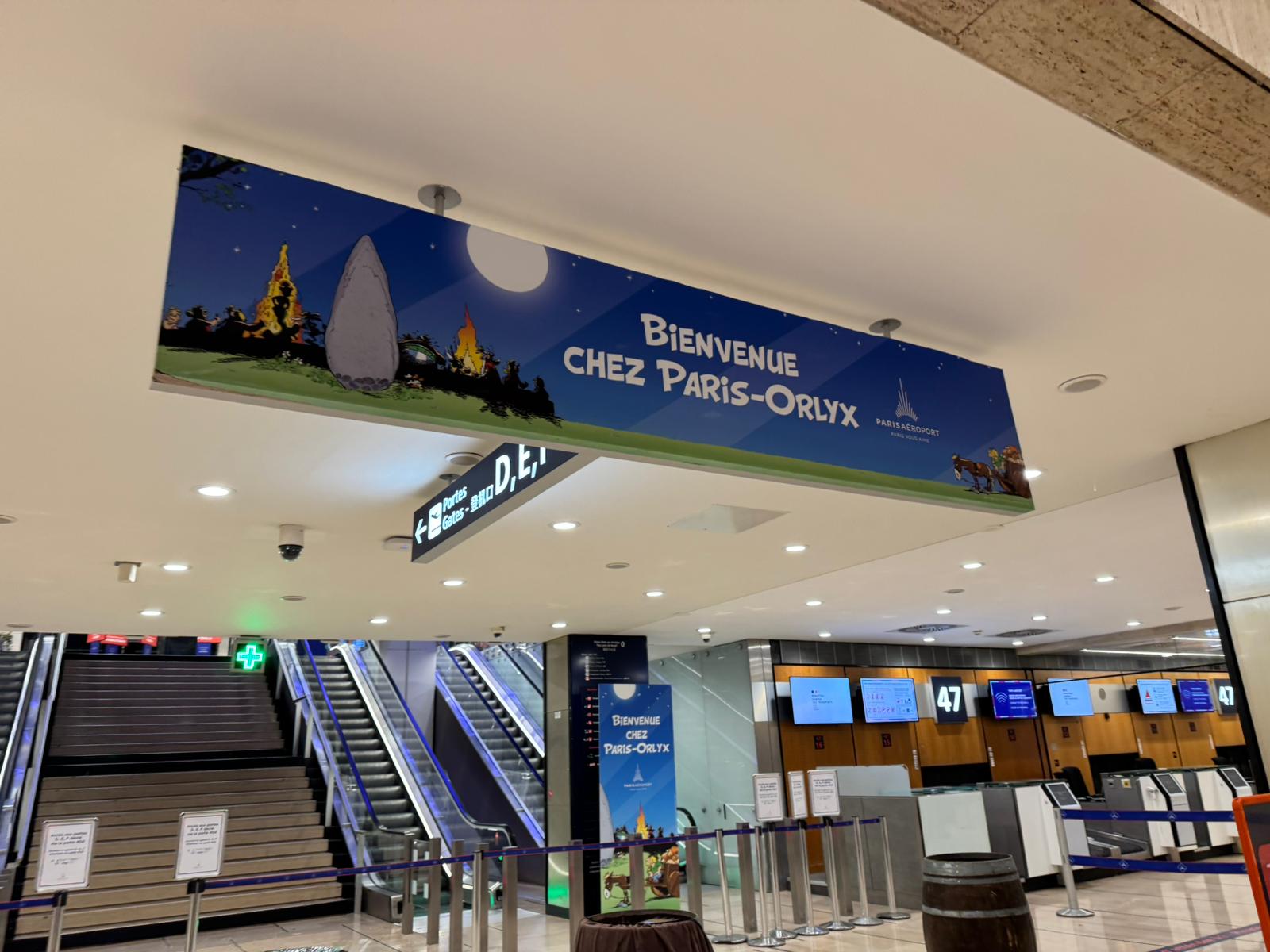 Panneau « Bienvenue chez Paris-Orly » posé au-dessus des escalators